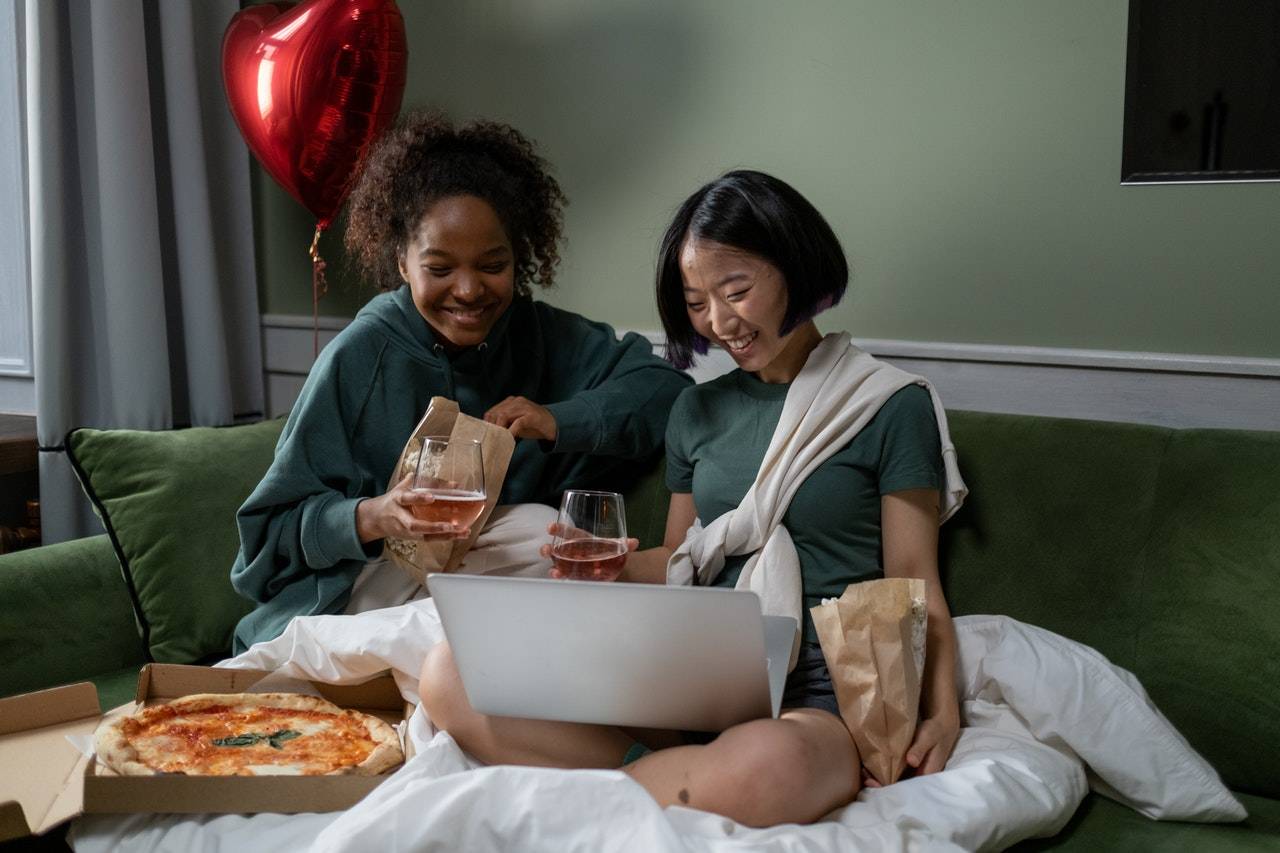 2 ladies watching movie on the bed with pizza and wine - darren yaw latest news 